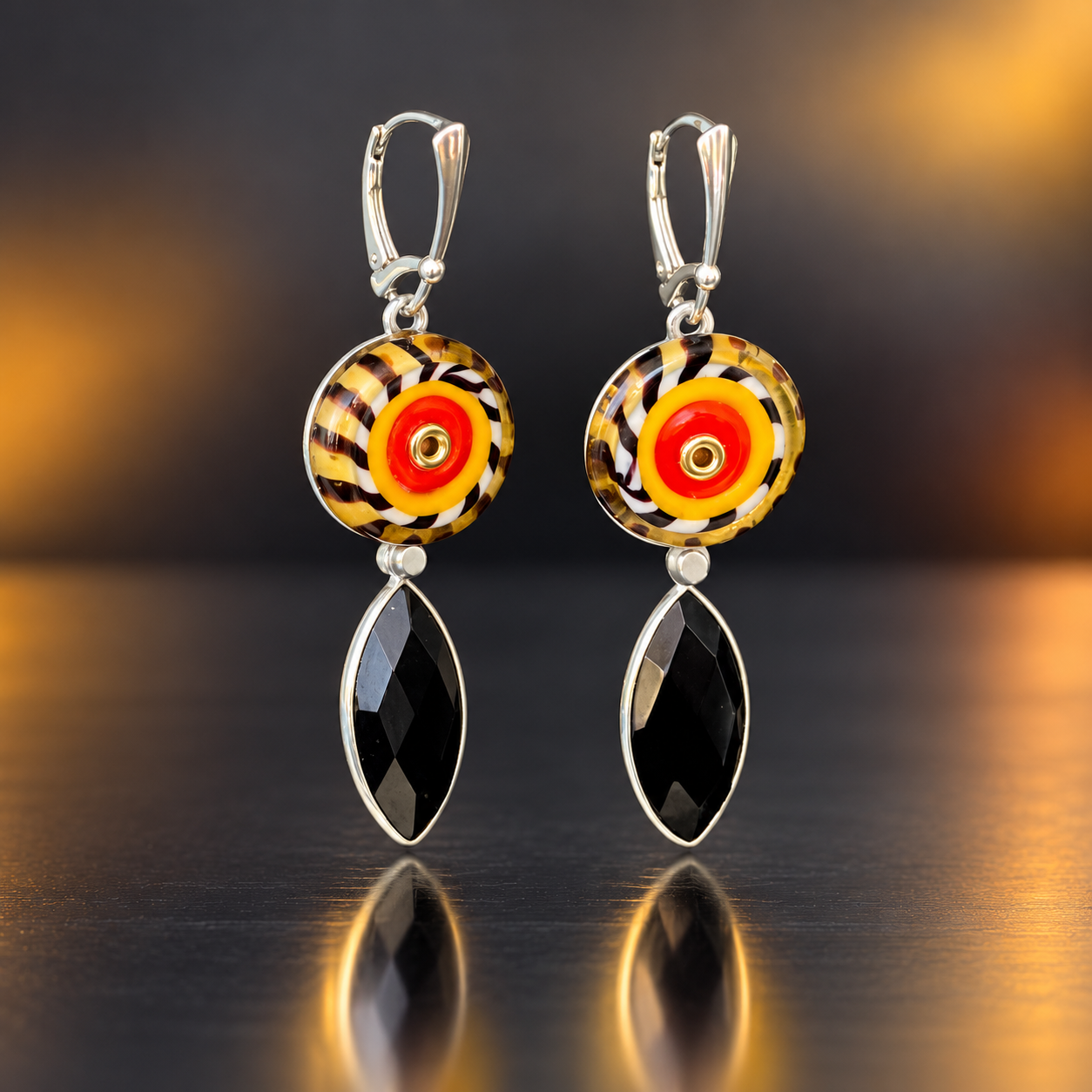 Amber, red, black and white patterned lampwork glass earrings with faceted black onyx drops, stainless steel discs and sterling silver leverback ear wires.