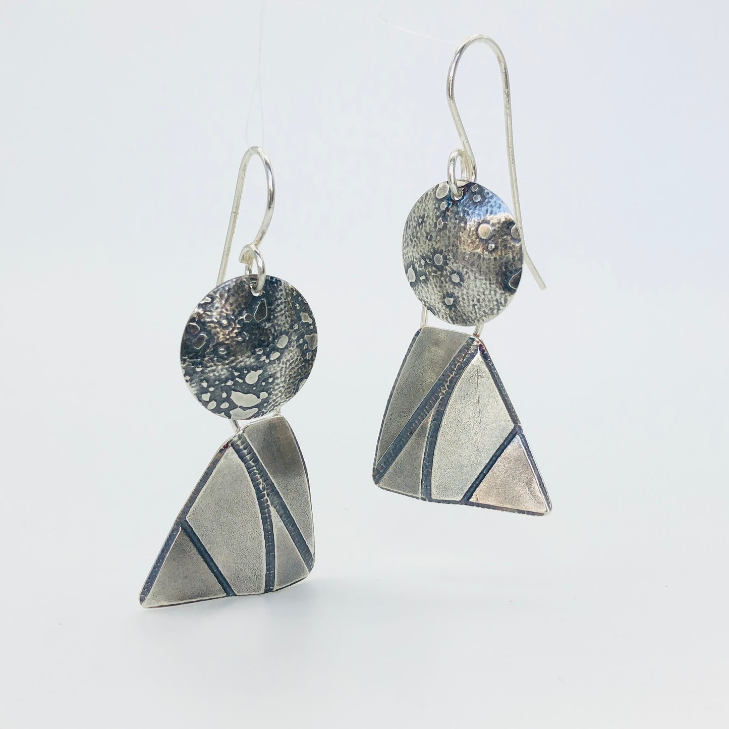 Dimensional geometric shapes combine together to resemble sailboats, angels or perhaps just the fun shapes they are of a circle and "4 sided" triangle. Great acid etched textures and movement with the two components dangling independently of each other.  "Score and bend" technique gives these earrings their 3 dimensional quality. These earrings measure 1 3/4" in length and 3/4" in width.