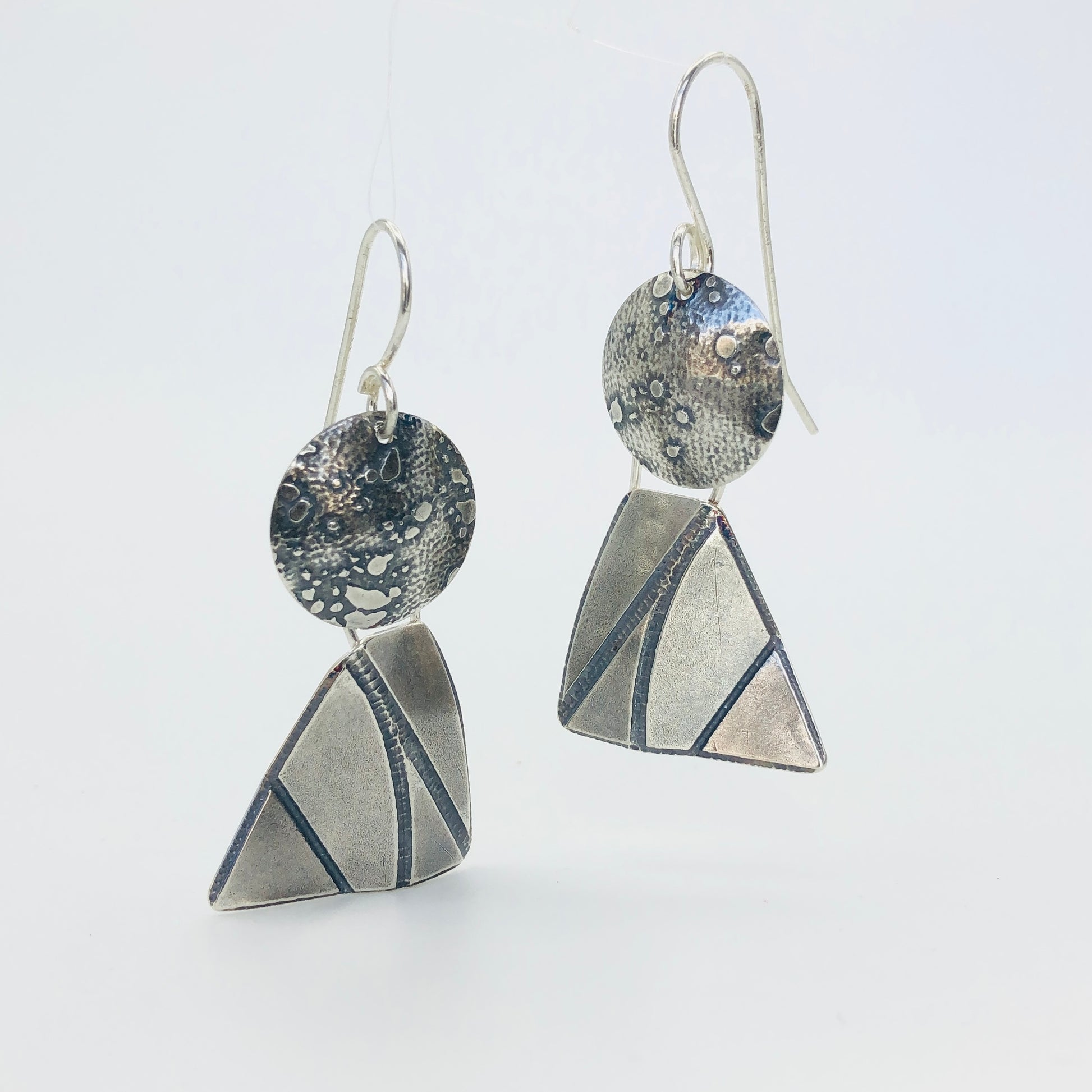 Dimensional geometric shapes combine together to resemble sailboats, angels or perhaps just the fun shapes they are of a circle and "4 sided" triangle. Great acid etched textures and movement with the two components dangling independently of each other.  "Score and bend" technique gives these earrings their 3 dimensional quality. These earrings measure 1 3/4" in length and 3/4" in width.